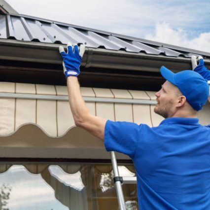 man installing house roof rain gutter system man installing house roof rain gutter system